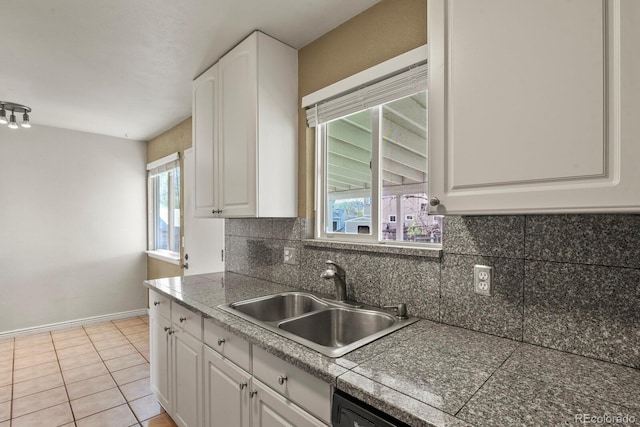 kitchen featuring baseboards, tile countertops, white cabinets, a sink, and backsplash