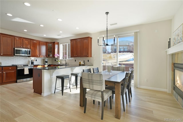 kitchen with decorative light fixtures, appliances with stainless steel finishes, backsplash, dark countertops, and glass insert cabinets