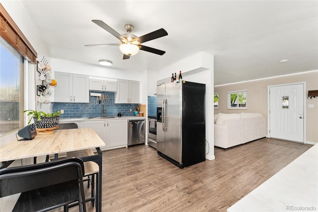 kitchen with stainless steel appliances, ceiling fan, wood finished floors, and light countertops