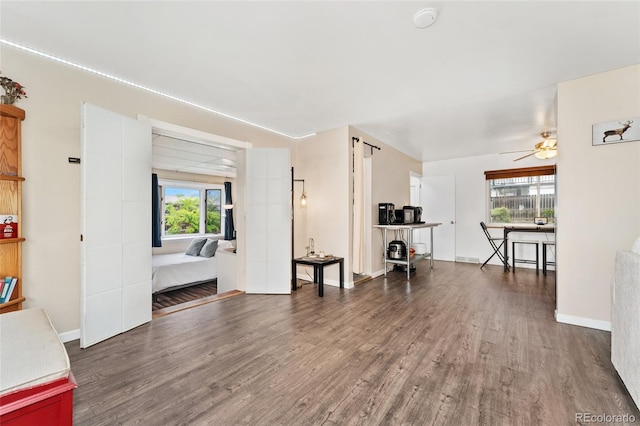 living area with wood finished floors, a ceiling fan, and baseboards