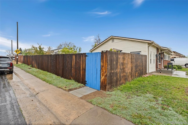 view of home's exterior with fence, concrete driveway, and a gate