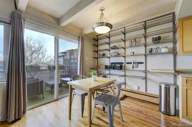 dining area featuring a textured ceiling, beamed ceiling, and light wood-type flooring