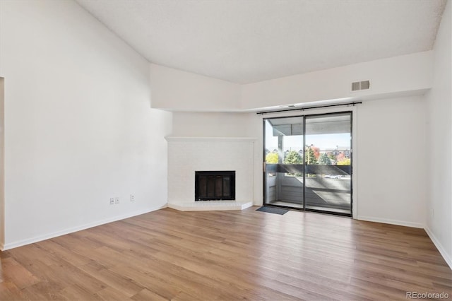 unfurnished living room with light hardwood / wood-style floors and a brick fireplace