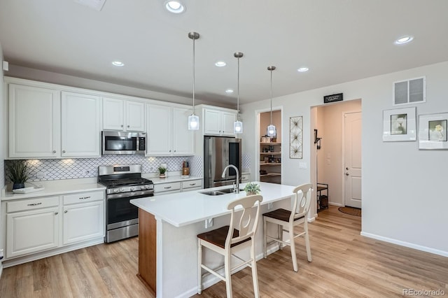 21837 E Stanford Cir, Aurora, CO 80015 - kitchen with appliances with stainless steel finishes, backsplash, a breakfast bar area, light wood-style flooring, and white cabinetry