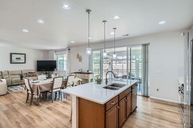 21837 E Stanford Cir, Aurora, CO 80015 - kitchen featuring brown cabinetry, light wood-style flooring, open floor plan, stainless steel dishwasher, and recessed lighting