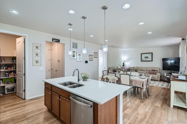 21837 E Stanford Cir, Aurora, CO 80015 - kitchen featuring stainless steel dishwasher, light wood finished floors, light countertops, open floor plan, and decorative light fixtures