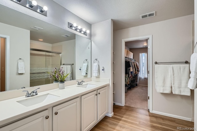 21837 E Stanford Cir, Aurora, CO 80015 - bathroom featuring double vanity, wood finished floors, a shower stall, and a spacious closet