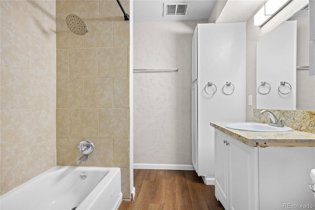 bathroom featuring hardwood / wood-style flooring, vanity, and tiled shower / bath combo