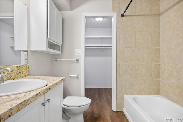 full bathroom featuring toilet, wood-type flooring, a textured ceiling, vanity, and tiled shower / bath combo