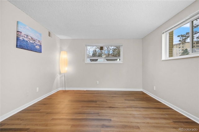 unfurnished room featuring hardwood / wood-style flooring and a textured ceiling