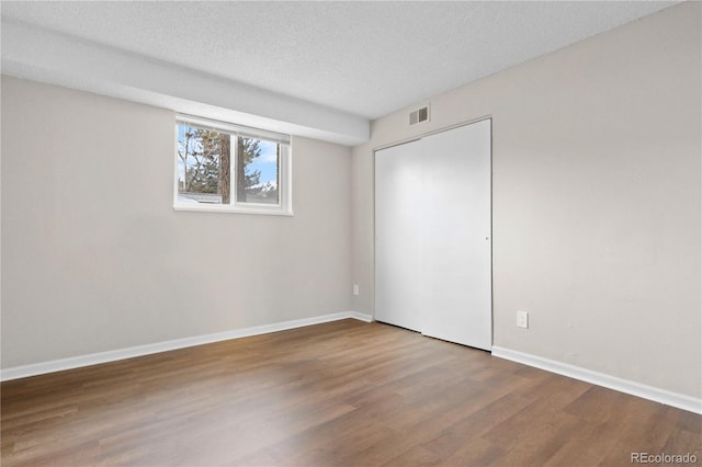 unfurnished room with wood-type flooring and a textured ceiling