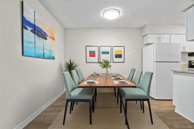 dining area with hardwood / wood-style flooring and a textured ceiling