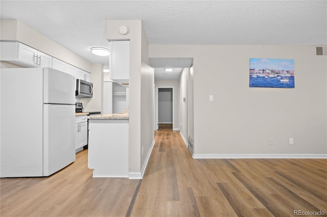 kitchen with appliances with stainless steel finishes, white cabinets, and light wood-type flooring