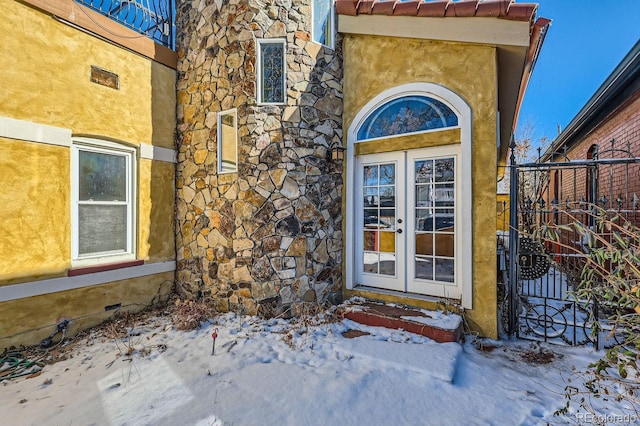 snow covered property entrance with french doors