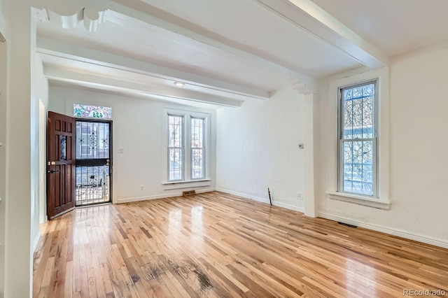 empty room featuring beam ceiling and light hardwood / wood-style flooring