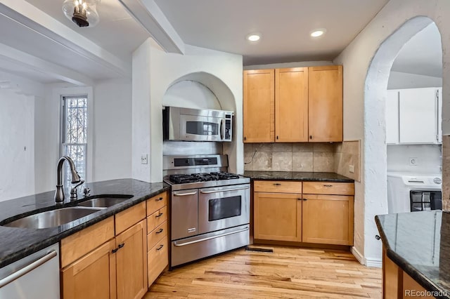 kitchen featuring stainless steel appliances, tasteful backsplash, dark stone countertops, and sink