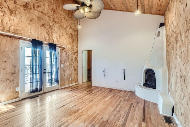 unfurnished living room featuring french doors, light wood-type flooring, ceiling fan, high vaulted ceiling, and wooden ceiling