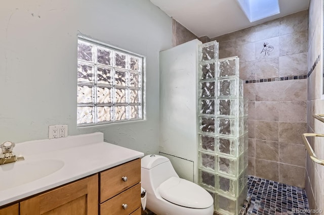 bathroom featuring vanity, toilet, a tile shower, and a skylight