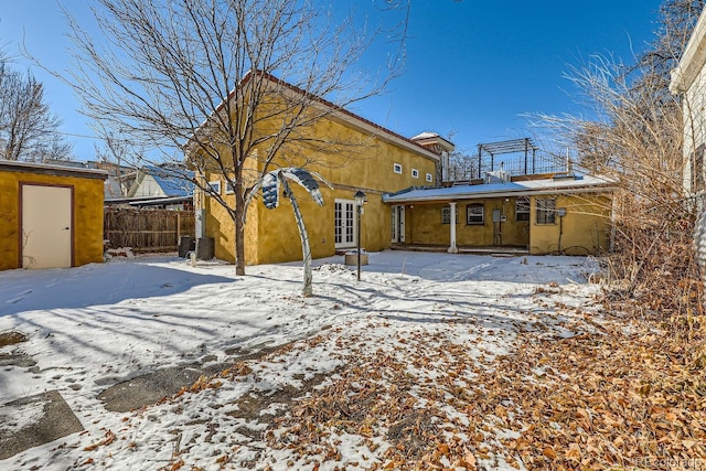 snow covered rear of property featuring french doors