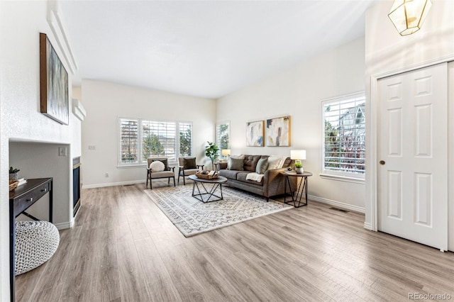 living room with plenty of natural light, a chandelier, and light hardwood / wood-style flooring