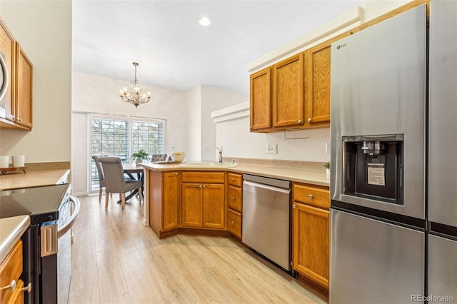 kitchen featuring sink, hanging light fixtures, light hardwood / wood-style floors, a chandelier, and appliances with stainless steel finishes