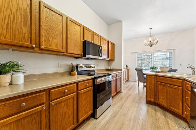 kitchen featuring sink, stainless steel appliances, an inviting chandelier, decorative light fixtures, and light wood-type flooring