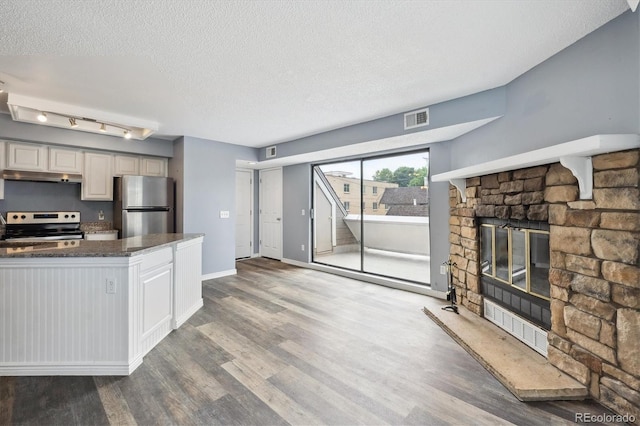 5250 S Huron Way Unit 1-204, Littleton, CO 80120 - kitchen with stainless steel appliances, under cabinet range hood, a textured ceiling, wood finished floors, and baseboards
