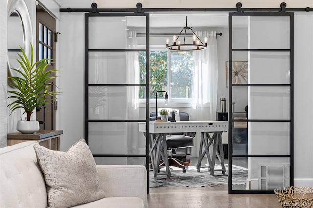 dining space featuring a barn door, hardwood / wood-style floors, and a notable chandelier