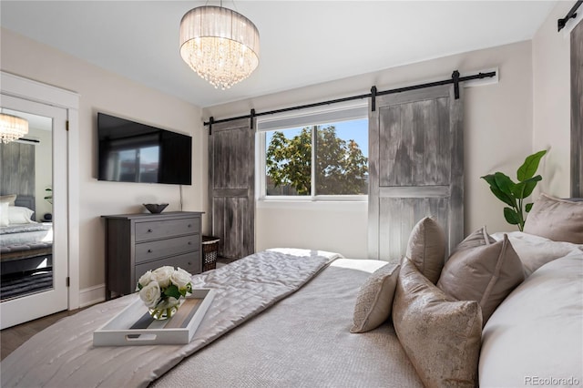 bedroom featuring a barn door, hardwood / wood-style floors, and a chandelier