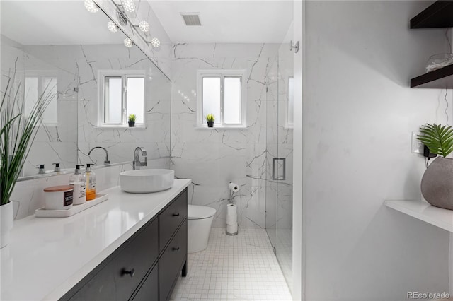 bathroom with vanity, a shower with door, tile walls, and toilet