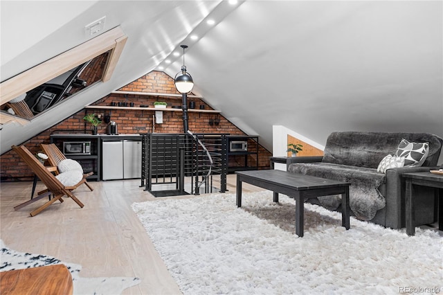 interior space featuring vaulted ceiling, brick wall, and light wood-type flooring