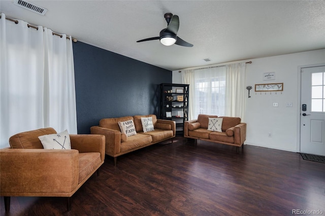 living room with ceiling fan, a textured ceiling, and dark hardwood / wood-style flooring