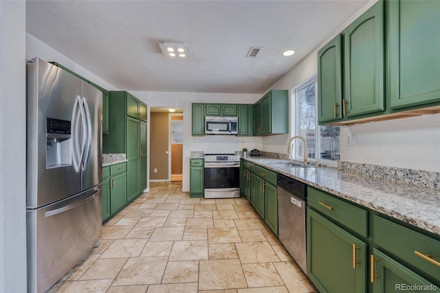 kitchen featuring stainless steel appliances, sink, light stone counters, and green cabinetry