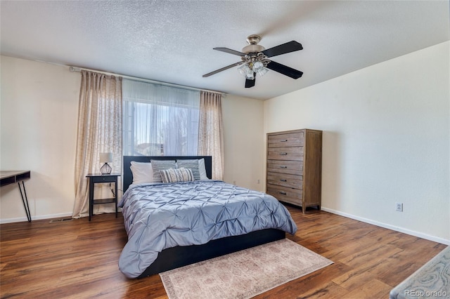 bedroom featuring dark wood-type flooring, ceiling fan, and a textured ceiling