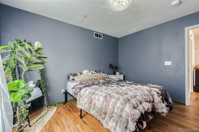 bedroom featuring hardwood / wood-style flooring and a textured ceiling