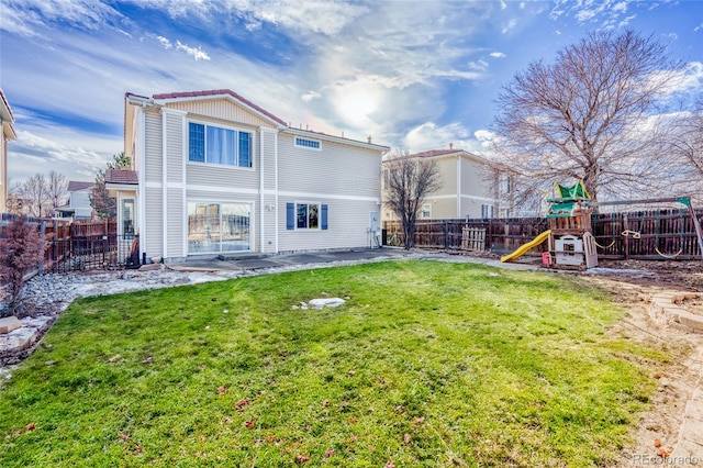 rear view of property featuring a playground and a yard