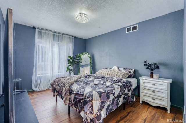 bedroom with dark hardwood / wood-style flooring and a textured ceiling