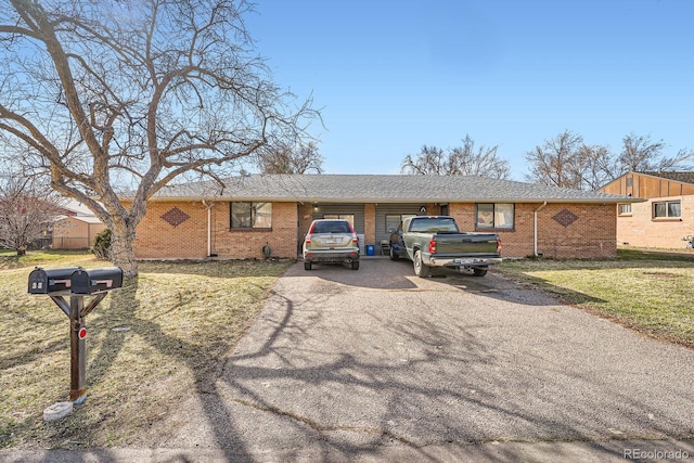 ranch-style house featuring aphalt driveway, brick siding, and a front yard