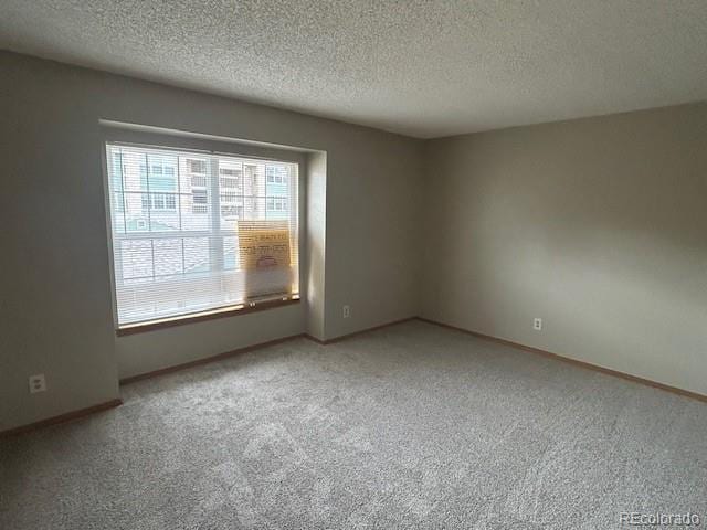 unfurnished room with carpet floors, a textured ceiling, and baseboards