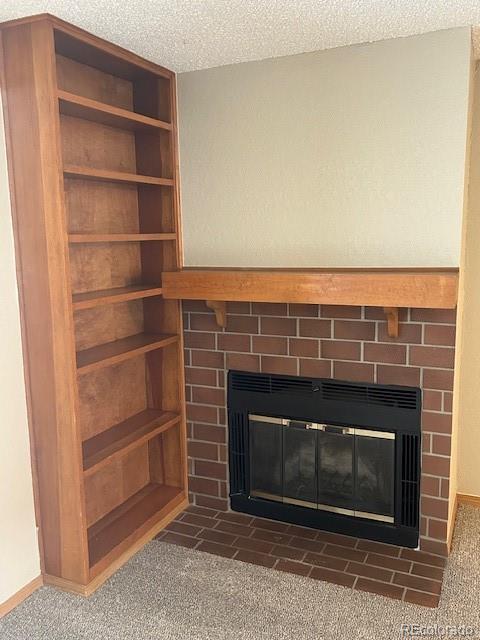 details featuring carpet flooring, a textured ceiling, a fireplace with flush hearth, and baseboards