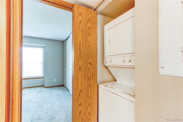 2690 E Otero Pl Unit 7, Centennial, CO 80122 - laundry area with stacked washer and clothes dryer, light colored carpet, a textured ceiling, baseboards, and a textured wall