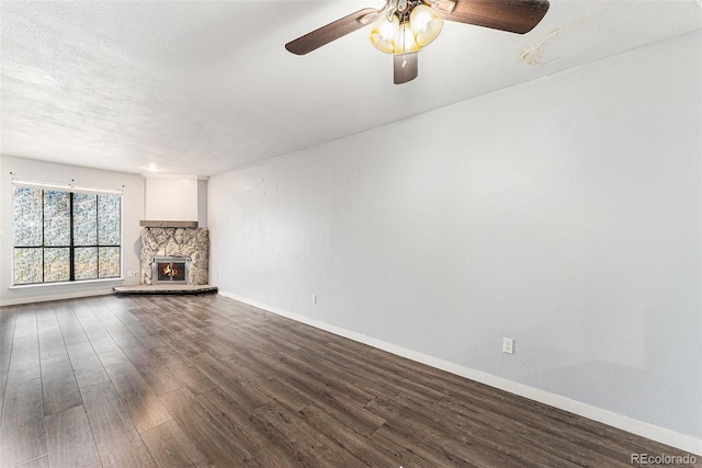 3550 S Harlan St Unit 105, Denver, CO 80235 - unfurnished living room featuring dark wood-style floors, a stone fireplace, and ceiling fan