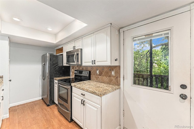 3550 S Harlan St Unit 105, Denver, CO 80235 - kitchen featuring appliances with stainless steel finishes, white cabinetry, backsplash, light wood-style floors, and a raised ceiling