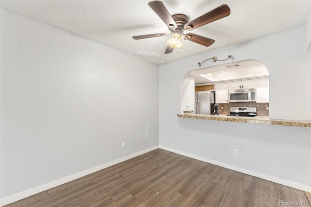 3550 S Harlan St Unit 105, Denver, CO 80235 - kitchen featuring stainless steel appliances, arched walkways, wood finished floors, white cabinets, and a ceiling fan