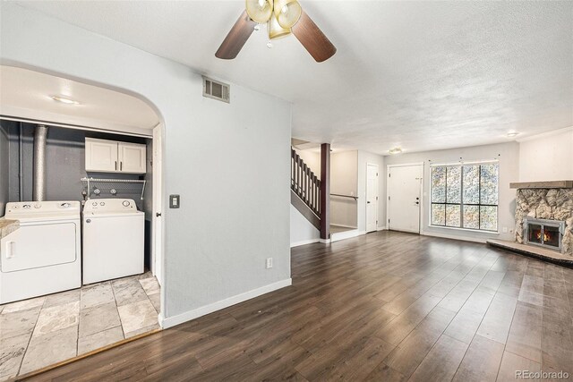 3550 S Harlan St Unit 105, Denver, CO 80235 - unfurnished living room featuring washing machine and dryer, ceiling fan, stairs, a fireplace, and arched walkways