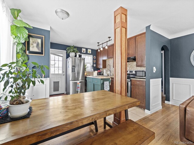 1221 Ulster St, Denver, CO 80220 - dining room featuring arched walkways, light wood-style floors, and a wainscoted wall