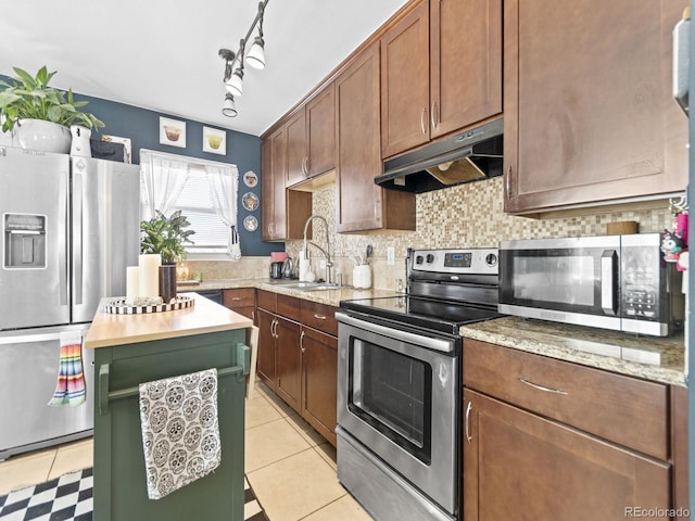 1221 Ulster St, Denver, CO 80220 - kitchen with stainless steel appliances, a sink, under cabinet range hood, backsplash, and a center island
