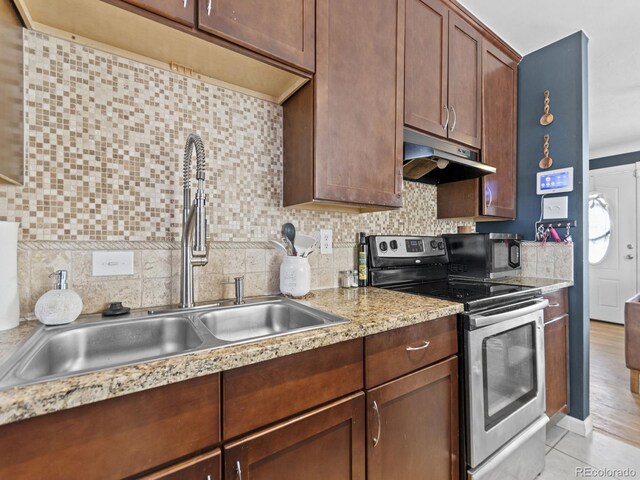 1221 Ulster St, Denver, CO 80220 - kitchen featuring under cabinet range hood, stainless steel range with electric cooktop, a sink, and decorative backsplash
