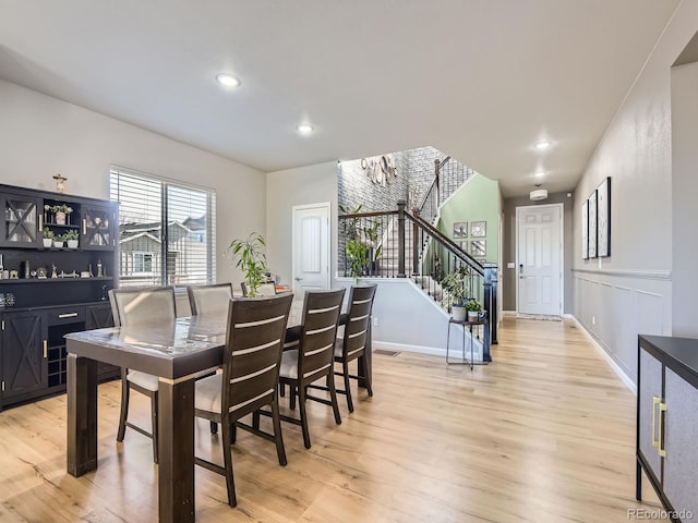 dining space with light hardwood / wood-style floors and an inviting chandelier