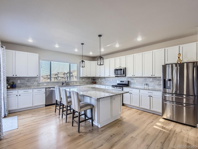 kitchen with white cabinets, a kitchen island, light wood-type flooring, and appliances with stainless steel finishes